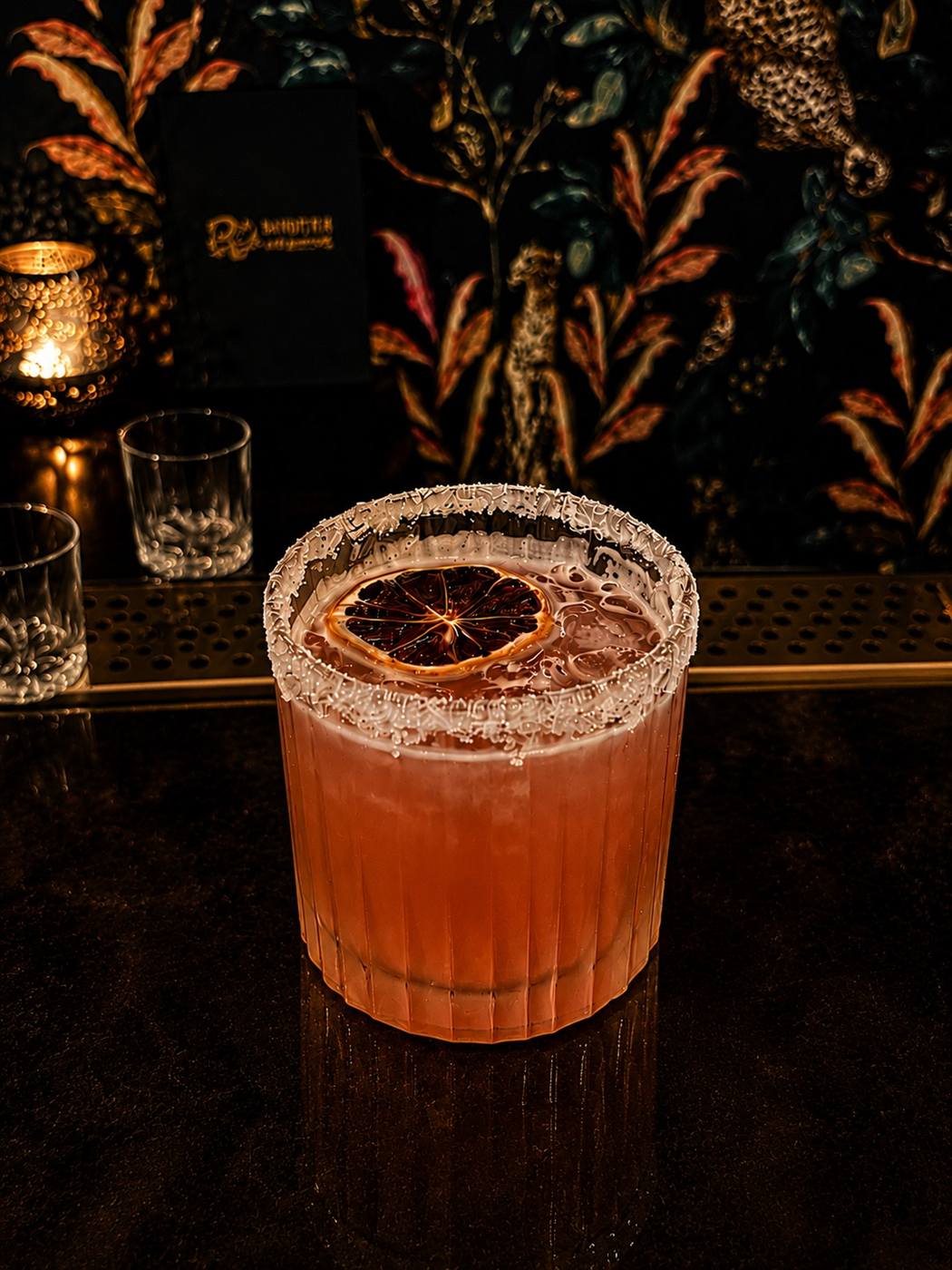 Amber cocktail on the bar by candlelight